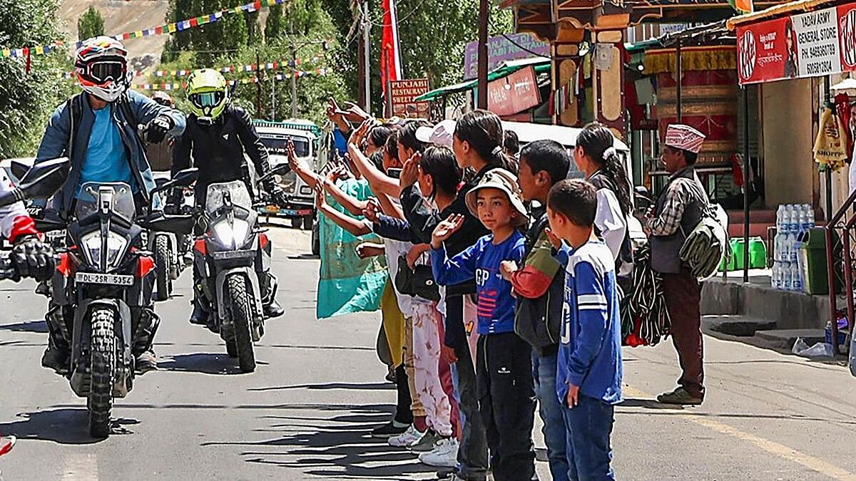 Congress leader Rahul Gandhi acknowledges the crowd while riding a motorcycle during his tour of the Union Territory of Ladakh.