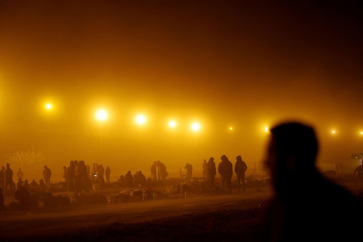 Migrants stand near the border wall during a sandstorm after having crossed the US-Mexico border to turn themselves in to US Border Patrol agents.