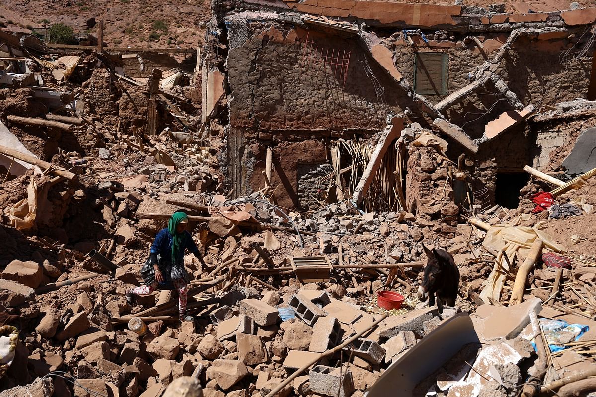 Khadijah Deaoune walks in the rubble next to her donkey, where her house once stood, as she tries to rescue her goat after the deadly earthquake in Tinmel, Morocco.