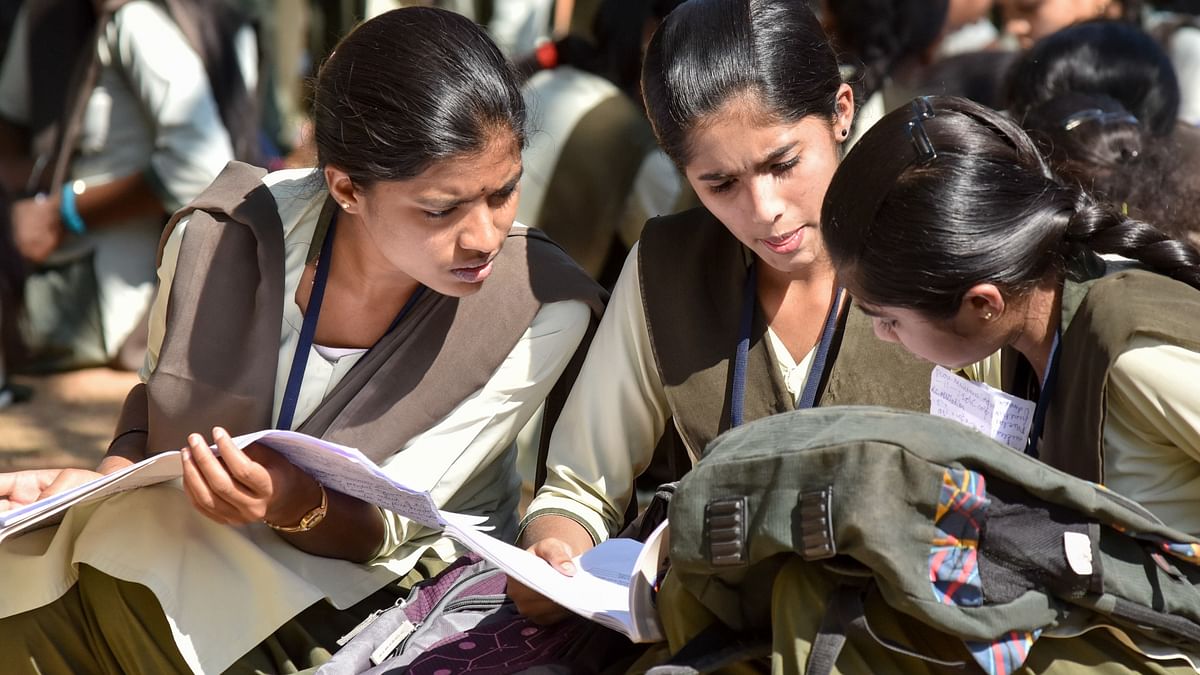 Students busy in last minute preparations for PUC Physics and Economies exam before entering the exam hall at Maharaja College in Mysuru on Thursday. - PHOTO / SAVITHA B R