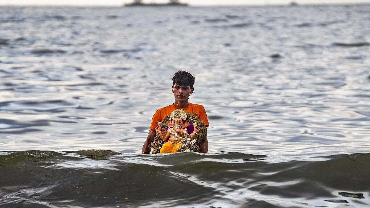 A volunteer carries an idol of Lord Ganesha for immersion in the Arabian Sea during the seventh day of Ganesh Chaturthi festival, in Mumbai.