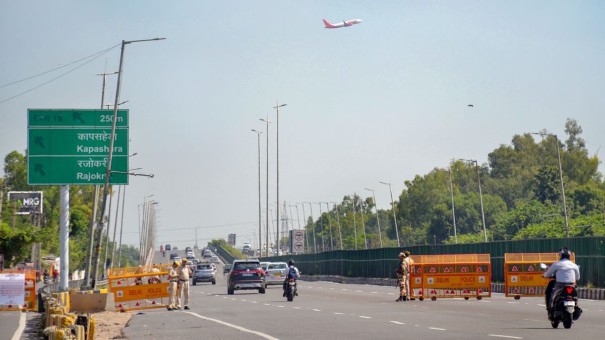 Security personnel stand guard near a police barricade at the Delhi-Gurugram Expressway as part of the  security arrangements for the G20 Summit in Gurugram.