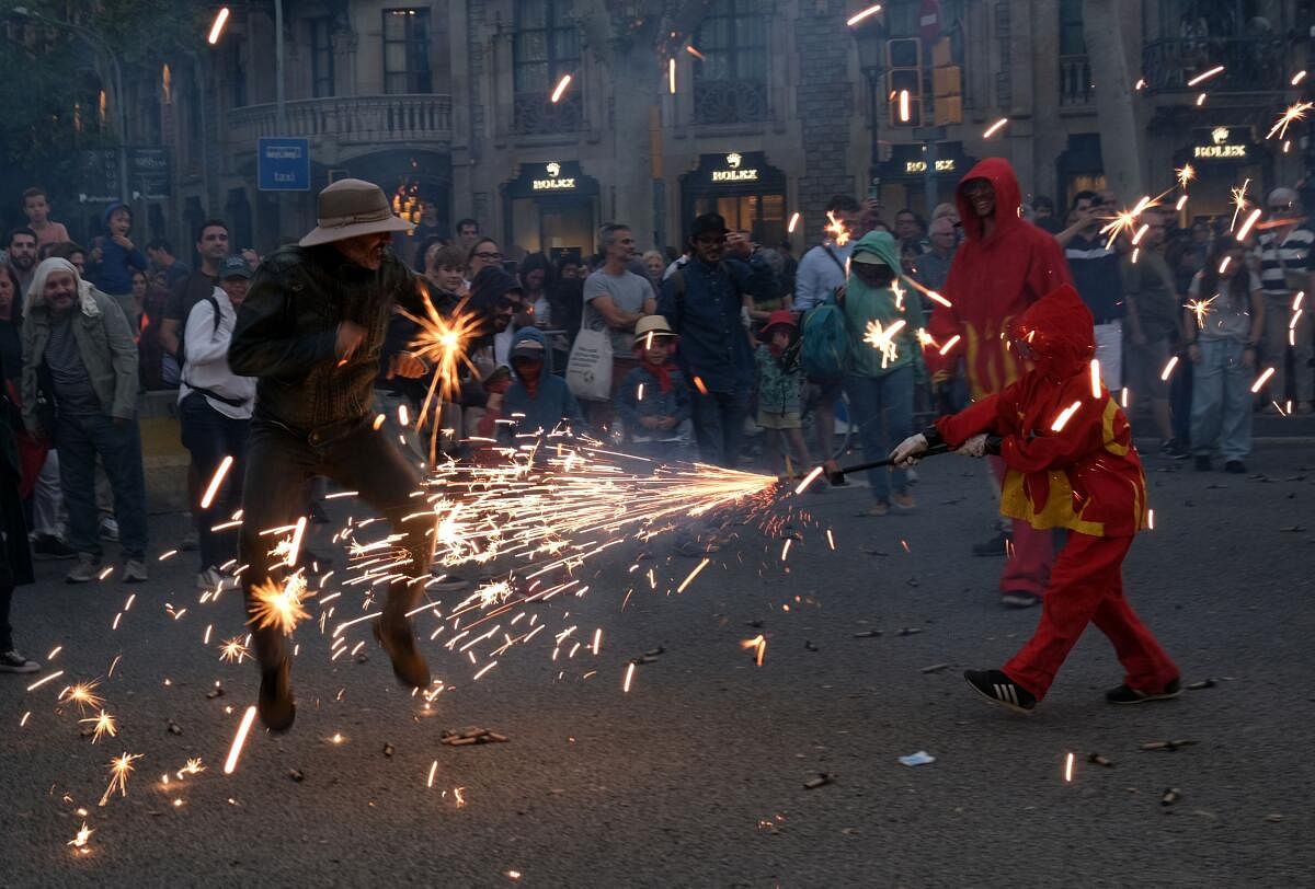 A performer dressed as a devil holds a stick with fireworks next to locals and tourists during the traditional "Correfoc" (fire run) to mark Barcelona's patroness, La Merce, in Barcelona. 