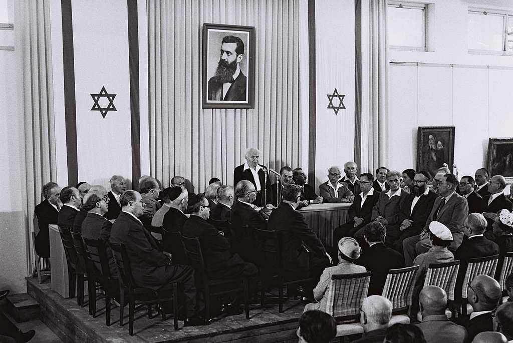 David Ben-Gurion, Israel's first Prime Minister, flanked by the members of his provisional government, reads the Declaration of Independence in the Tel Aviv Museum Hall.