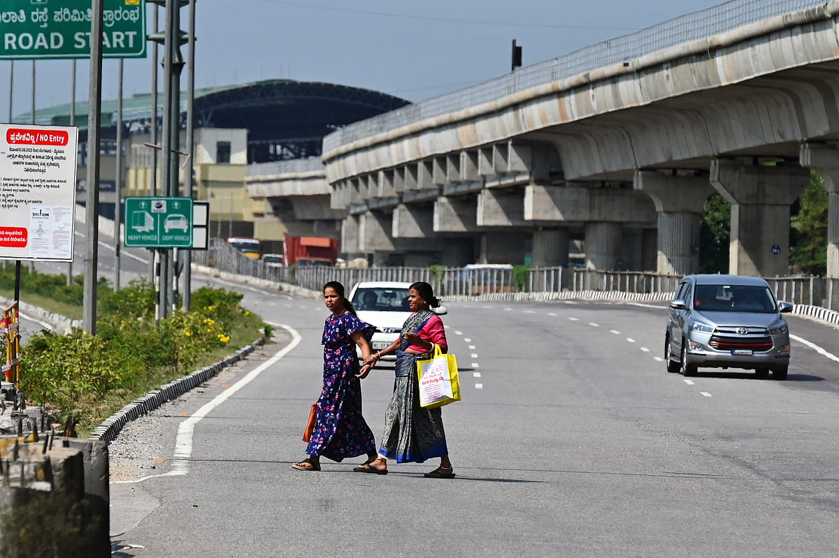 People struggle to cross the busy Bengaluru-Mysuru highway near the Challaghatta station.