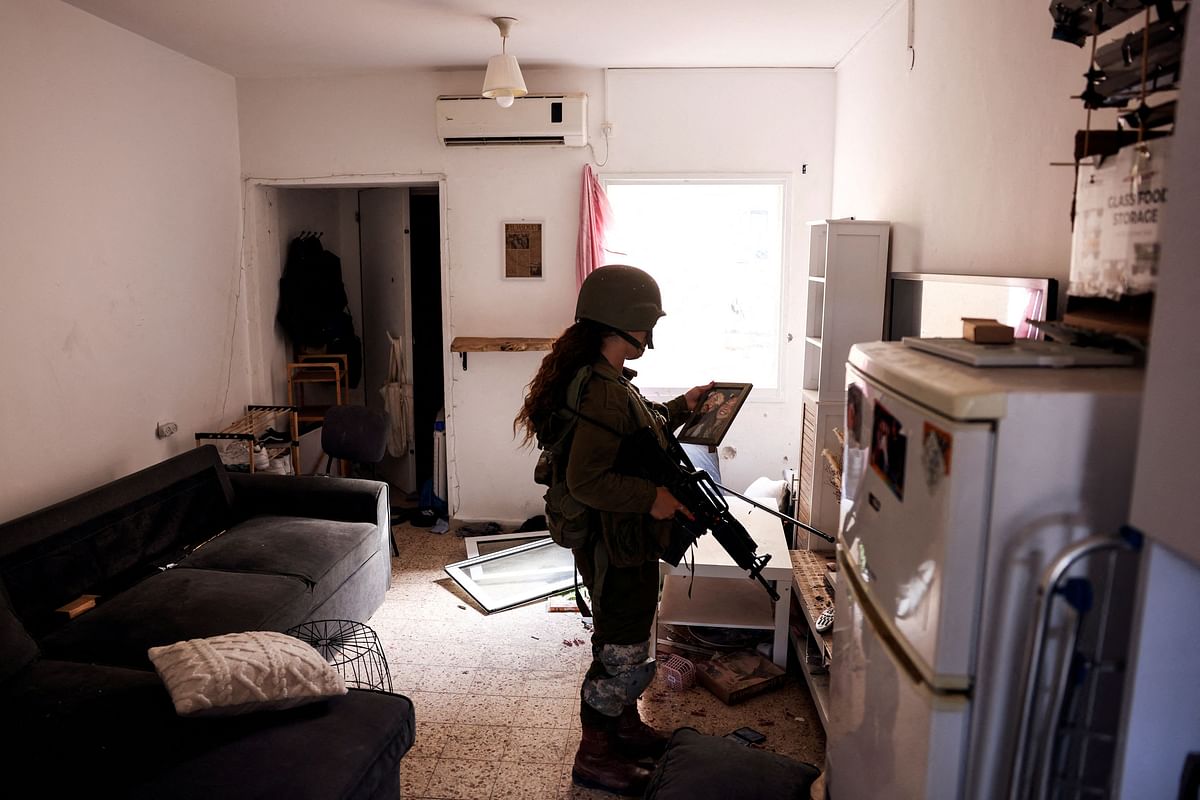 An Israeli soldier looks at a family photograph in an abandoned home, following a deadly infiltration by Hamas gunmen from the Gaza Strip, in Kibbutz Kfar Aza in southern Israel, October 15, 2023. 