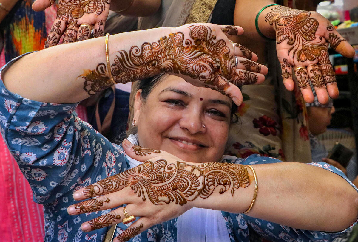 A woman poses for photos showing her hands decorated with henna ahead of 'Karva Chauth' festival, in Nagpur. 