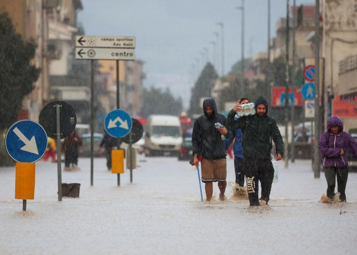 People walk in a flooded street in the aftermath of Storm Ciaran, in Oste, in Tuscany region, Italy.