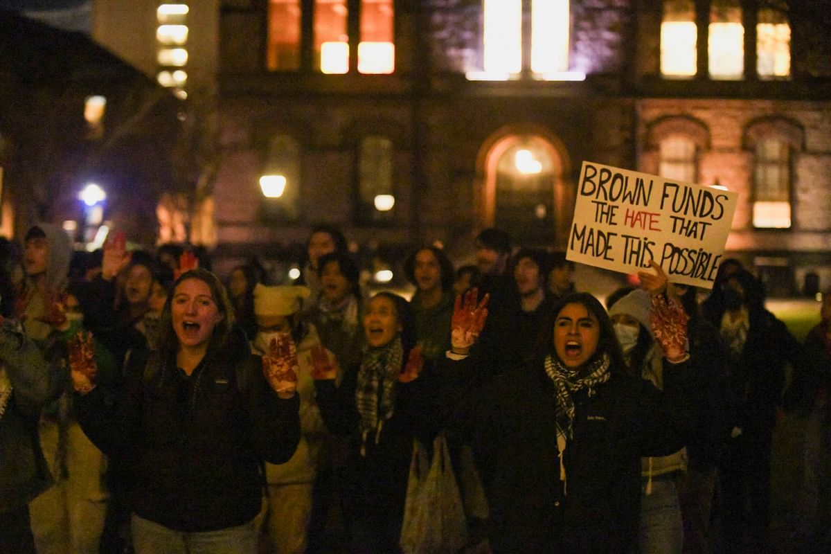 People hold up signs and protest following a vigil held on the grounds of Brown University, after three students of Palestinian descent were shot and wounded in Vermont, at the school's main green in Providence, Rhode Island, U.S. November 27, 2023. 