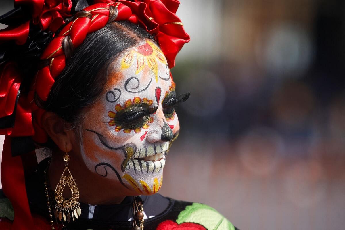A woman with her face painted as the popular Mexican figure "Catrina" smiles during the Day of the Dead celebrations, in Mexico City.