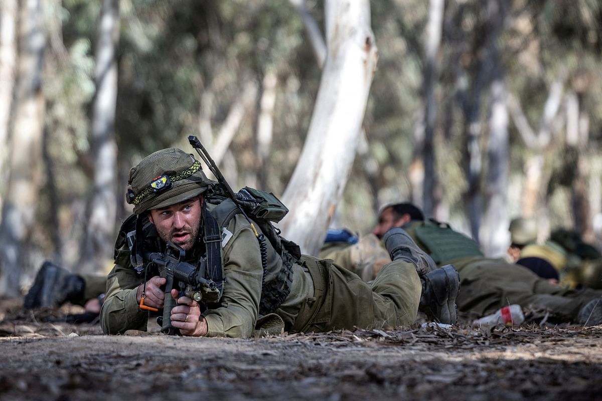 Israeli soldiers take cover after a warning of potential incoming fire from Gaza at the site of the surprise attack launched by Hamas on October 7th during a dance party near Reim, Israel, November 6, 2023.