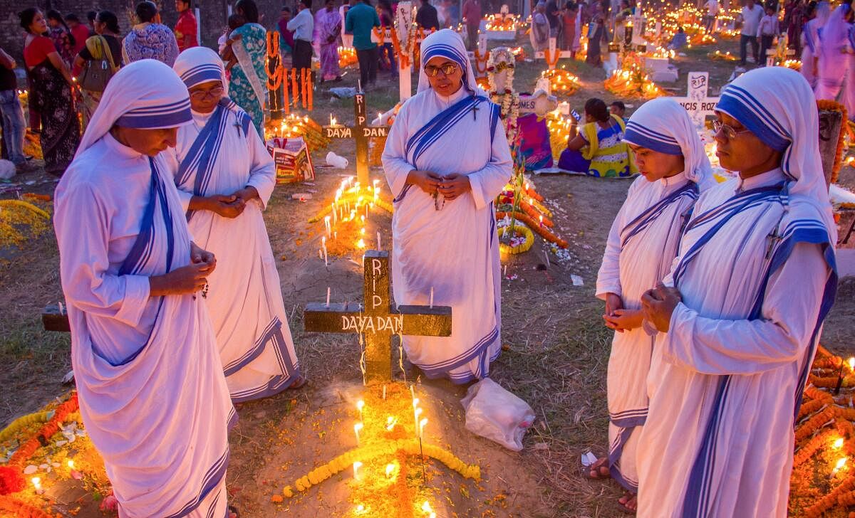 Christians nuns offer near a grave at a cemetery on All Souls Day in Nadia. 