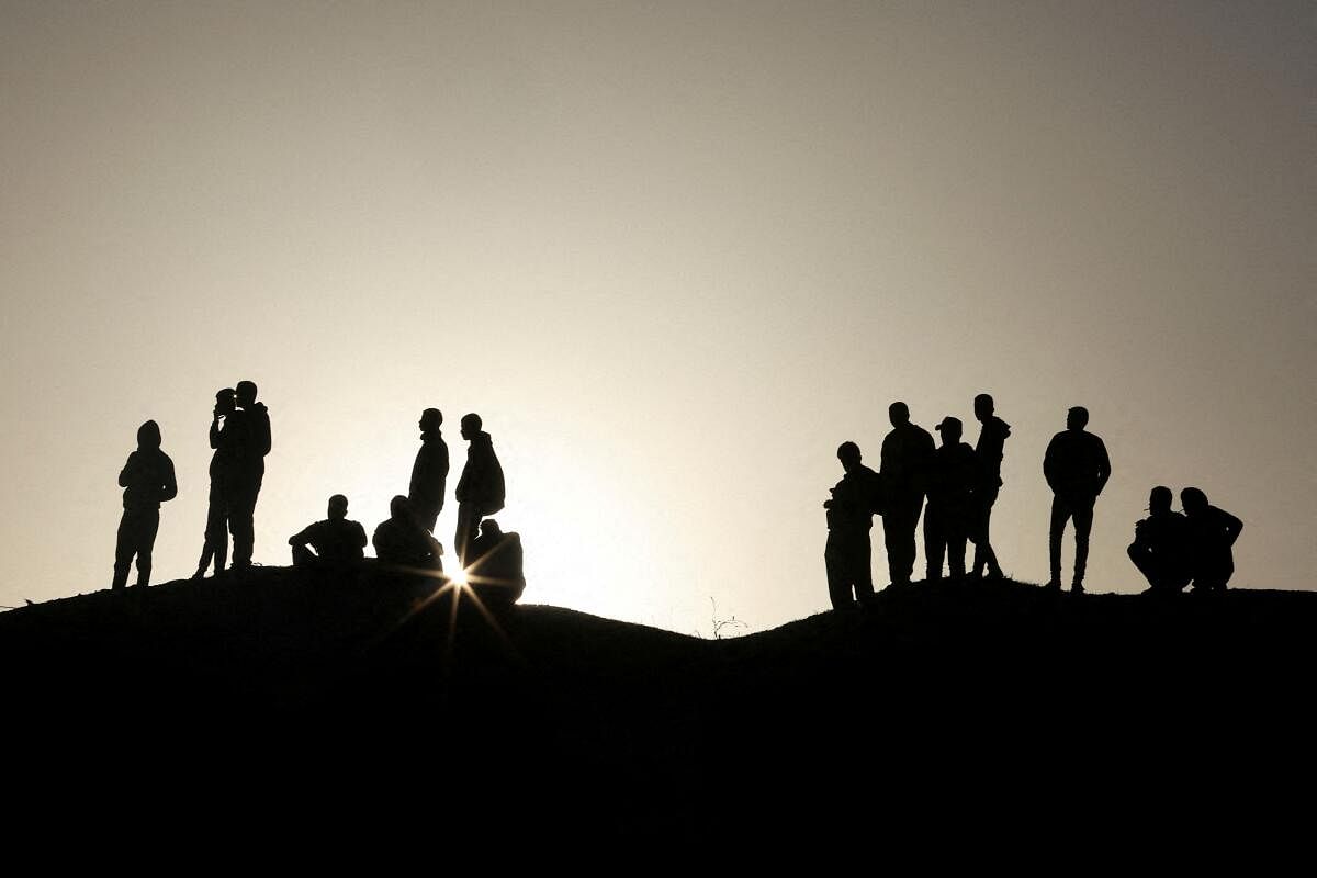 People wait for burial of Palestinians, who were killed by Israeli strikes and fire, after their bodies were released by Israel, amid the ongoing conflict between Israel and the Palestinian Islamist group Hamas, at a mass grave in Rafah, in the southern Gaza Strip, December 26, 2023. 