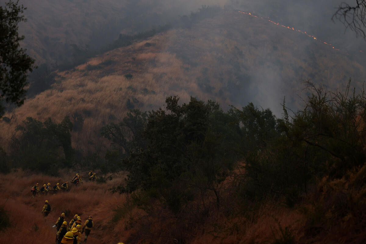 Firefighters walk as they assist in extinguishing wildfire burning in parts of the rural areas of Santiago, Chile.