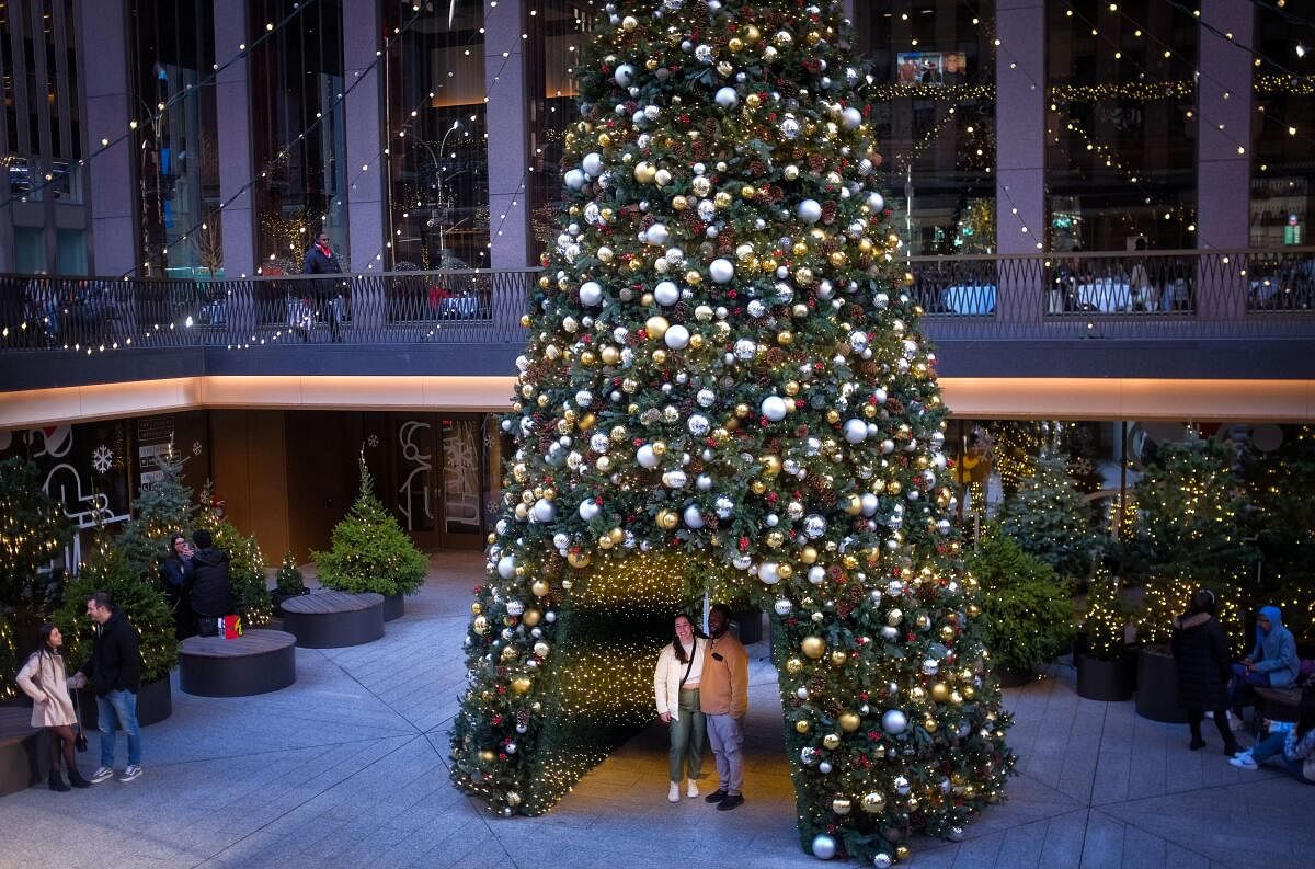 People pose beneath a Christmas tree display in midtown Manhattan, in New York City.