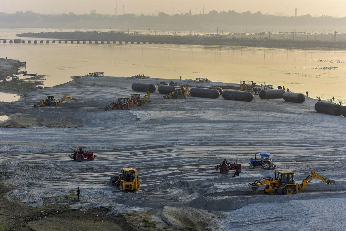 Backhoe loaders and tractors level the ground at the bank of the River Ganga ahead of the upcoming annual Hindu religious fair 'Magh Mela', in Prayagraj.
