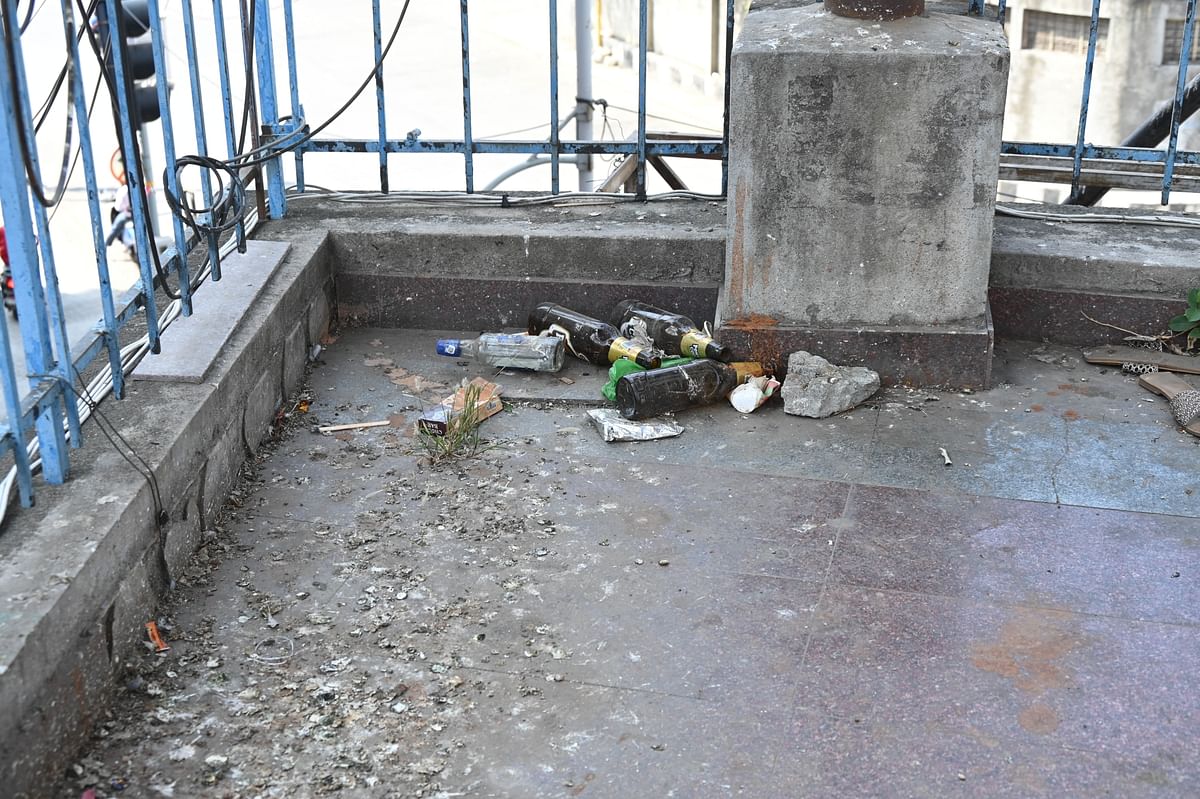 Empty liquor bottles are scattered along the pedestrian skywalk on KG Road. 