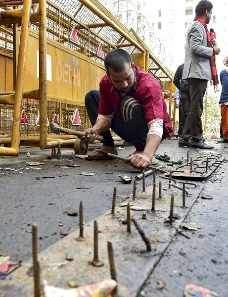  A worker removes nails, placed to block farmers from marching towards the national capital.