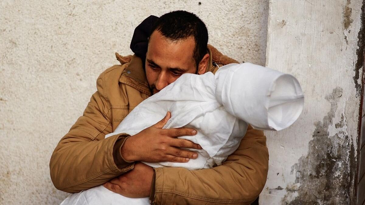 A Palestinian man reacts while carrying the body of his daughter who was killed in an Israeli strike, amid the ongoing conflict between Israel and Hamas, at Abu Yousef Al-Najjar hospital, in Rafah.