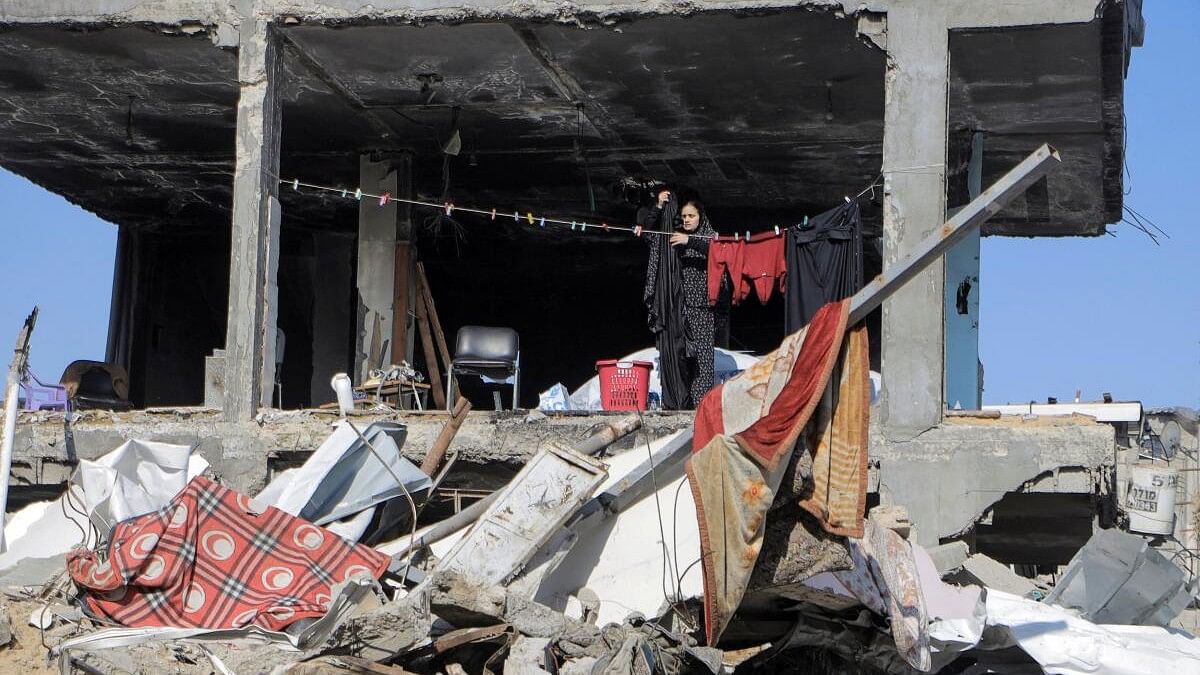 A Palestinian hangs clothes next to a destroyed building, in Jabalia refugee camp.