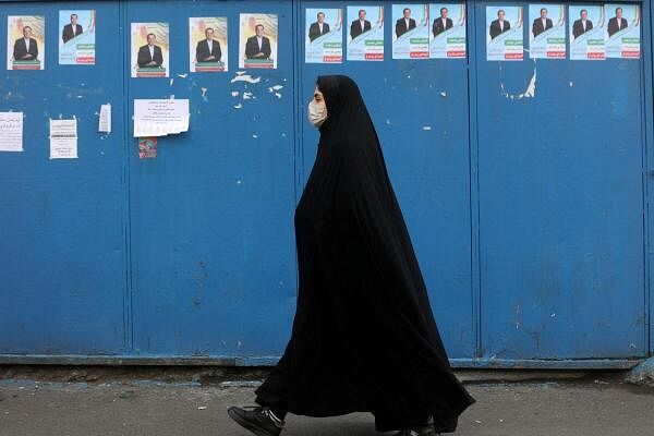 An Iranian woman walks past campaign posters for the parliamentary election in Tehran, Iran, February 27, 2024. 