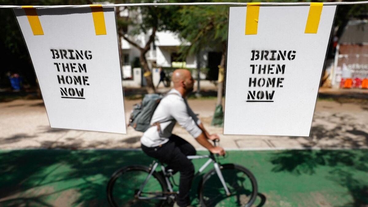 A man rides a bicycle past signs calling for the release of hostages kidnapped in the deadly October 7 attack on Israel by the Palestinian Islamist group Hamas from Gaza, in Tel Aviv, Israel March 4, 2024.