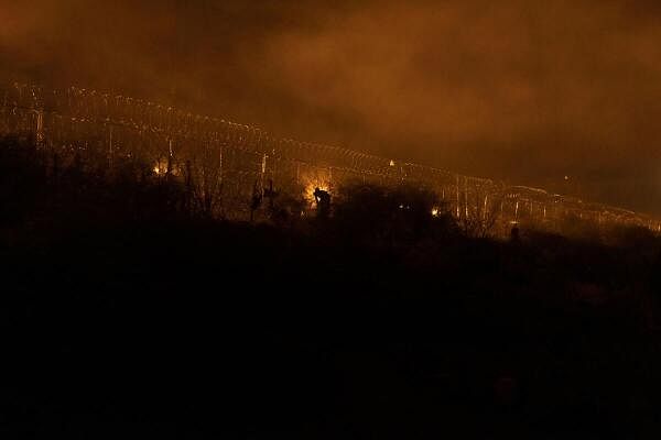 Migrant shears past razor wire fence to enter the United States in El Paso.