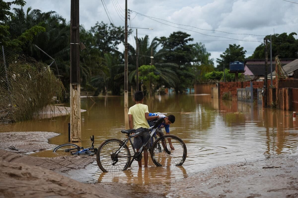 Children wash mud from their bicycles in the street after the Acre River overflowed due to heavy rain, in Brasileia, Brazil.