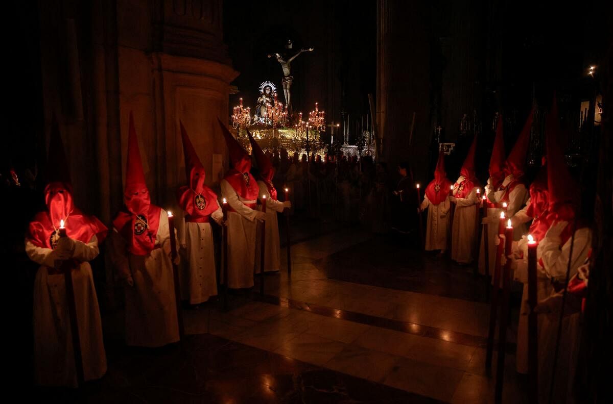 Penitents carry a statue of Christ on a weighted structure, traditionally known as 'trono', while others hold candles as they take part in a penitence act inside a church after the governing body of Silencio brotherhood decided that penance could not be carried out in the streets due to the heavy rain of the Nelson storm during the Holy Week in Ronda, Spain.