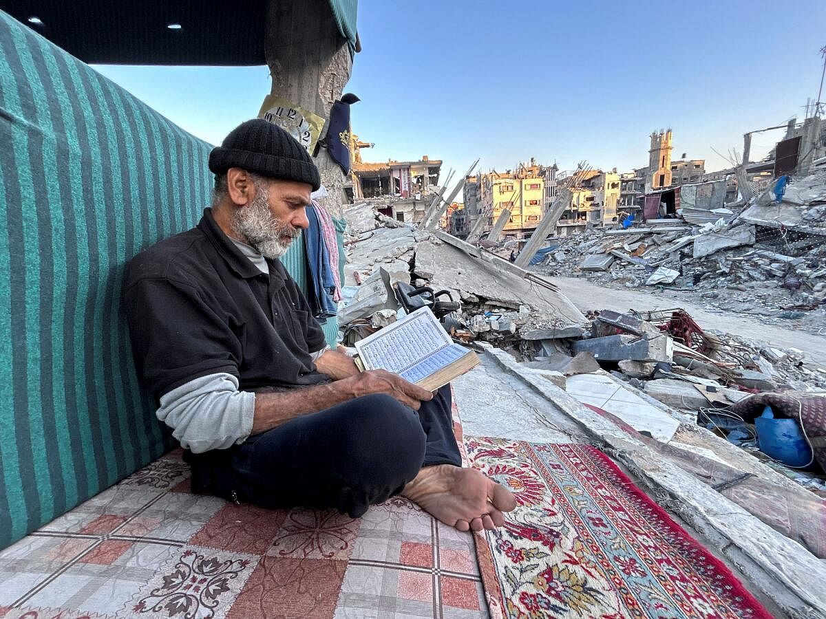 Palestinian man Ismail Al-Khlout reads the Koran as he waits to break his fast while sitting on the rubble of his house, which was destroyed during Israel's military offensive as the conflict between Israel and Hamas continues, during the holy month of Ramadan, in Beit Lahia in the northern Gaza Strip, March 13, 2024.