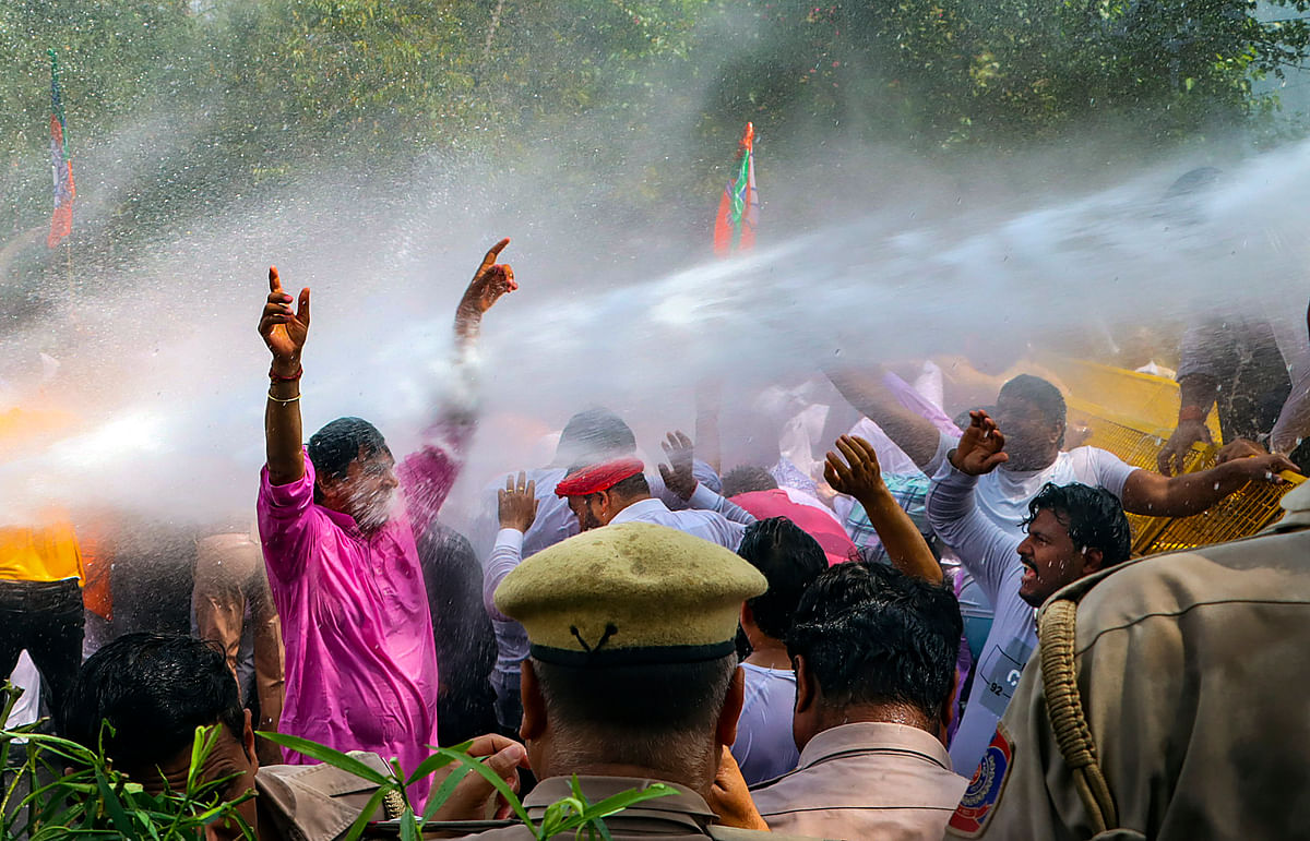 Protestors shout slogans as the Delhi police use water cannon to disperse BJP workers during their protest demanding the resignation of Delhi Chief Minister.