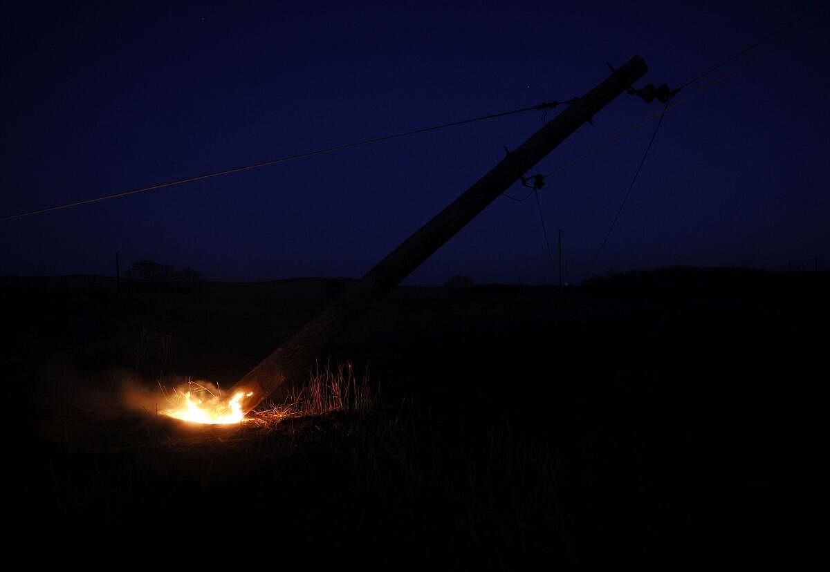 A power pole burns at its base in an area almost entirely burned by a recent wildfire near Canadian, Texas.