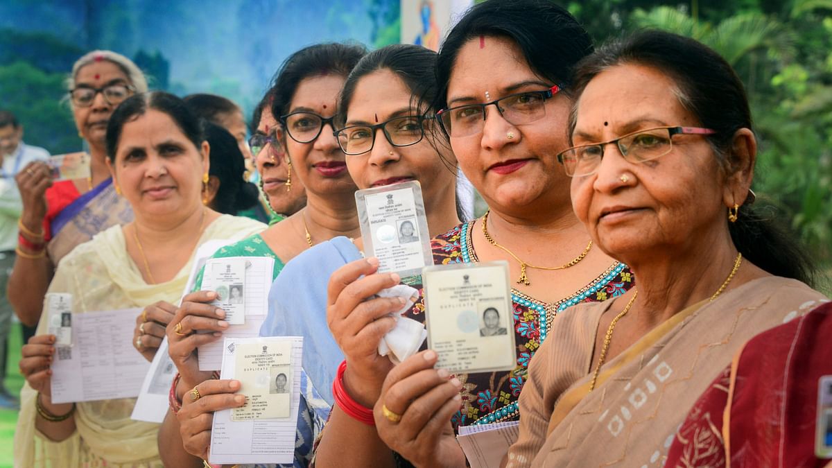 Voters show their identification cards as they wait in queues at a polling station to cast their votes for the first phase of Lok Sabha elections, in Bastar.