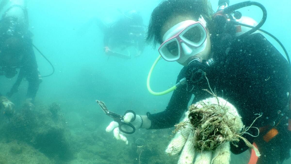 A scuba diver shows to the camera abandoned fishing nets removed from a coral reef in Phuket, Thailand.