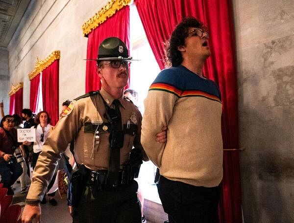 Tennessee State Troopers detain a gun reform activist after the Republican Speaker of The House ordered the House gallery cleared following a vote by the House to adopt Senate Bill 1325 at the Tennessee State Capitol building in in Nashville, Tennessee, US, April 23, 2024. The bill will authorize teachers, principals, and school personnel to carry a concealed handgun on school grounds. 
