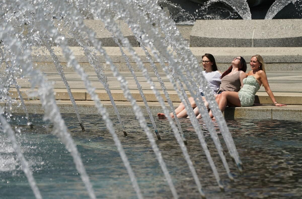 Women dip their feet in the cool fountain at the World War II Memorial on a possible record setting heat day in Washington, U.S., April 29, 2024.