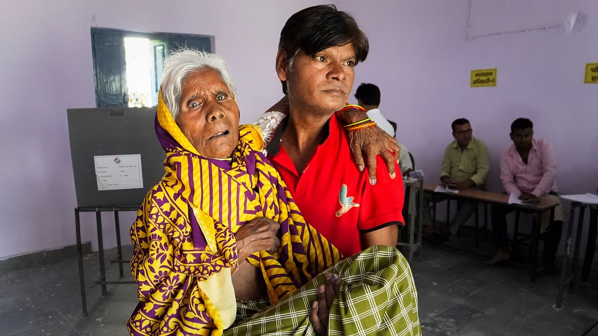 An elderly voter being assisted as she arrives to cast her vote for the first phase of Lok Sabha elections, in Bharatpur, Rajasthan.