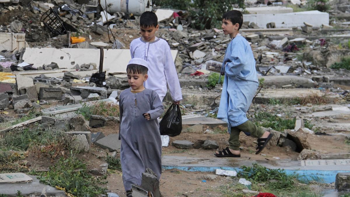 Children walk as Palestinians visit the graves of people who were killed in the ongoing conflict between Israel and the Palestinian Islamist group Hamas, in Gaza Strip.