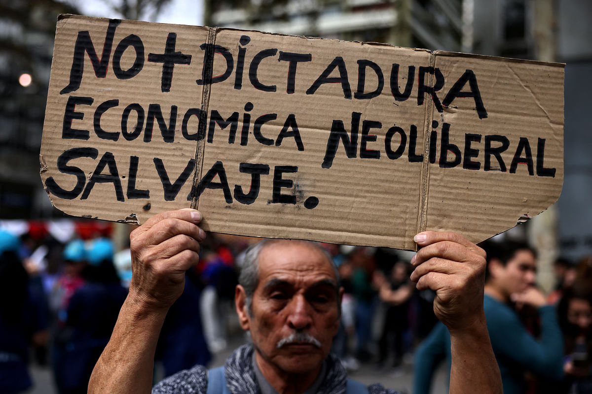A Chile’s union worker holds up a sign that reads 'No more savage neoliberal economic dictatorship' during a nationwide strike to demand new labour policy, in Santiago, Chile April 11, 2024.