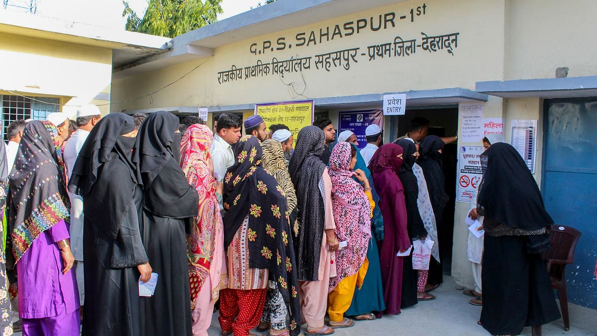 Voters wait in a queue at a polling station to cast their votes for the first phase of Lok Sabha elections, in Dehradun.