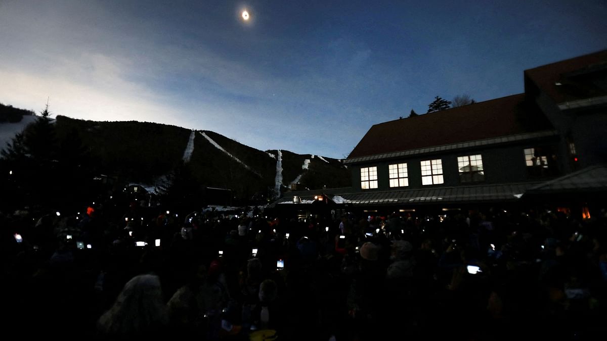 The sky darkens as people take photos with their phones of the total solar eclipse at Sugarbush ski resort in Warren, Vermont, US.
