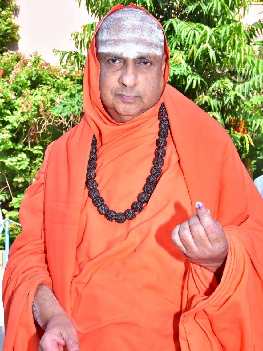 Suttur Mutt seer Shivaratri Deshikendra Swami shows his ink-marked finger after casting his vote in Mysuru.