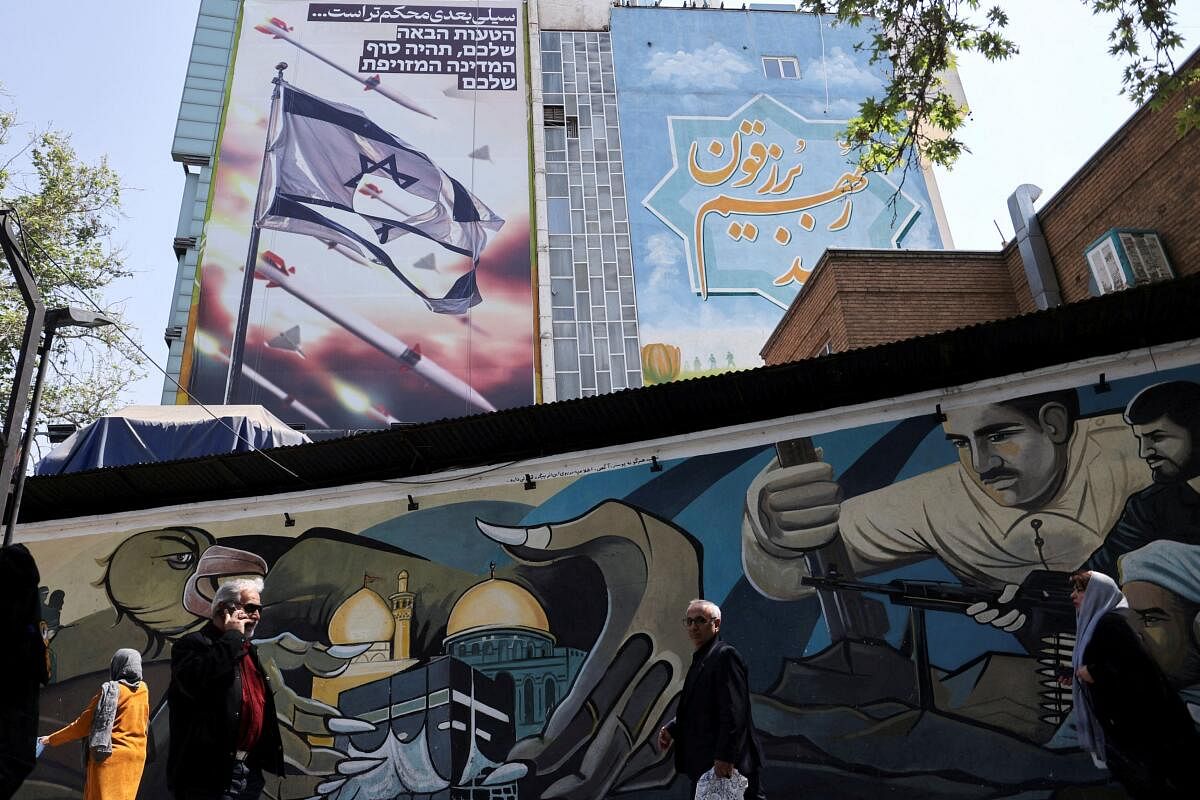 People walk below an anti-Israel billboard on a street in Tehran, Iran April 14, 2024. Majid 
