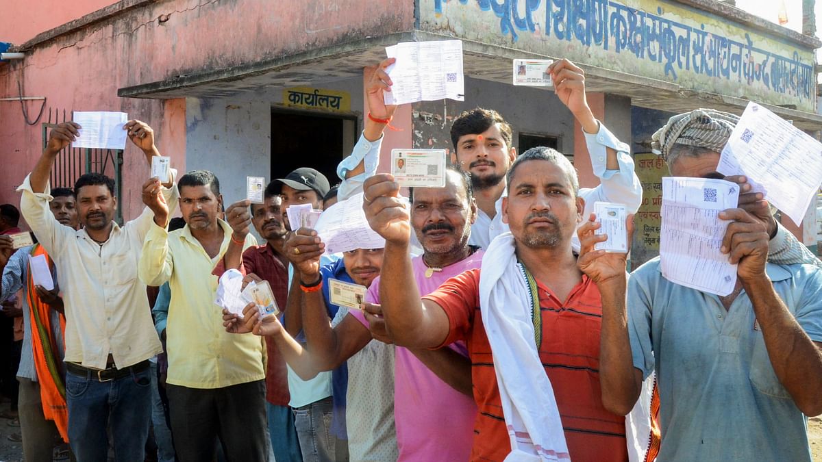 Voters show their identification cards as they wait in queues at a polling station to cast their votes for the first phase of Lok Sabha elections, in Gaya.