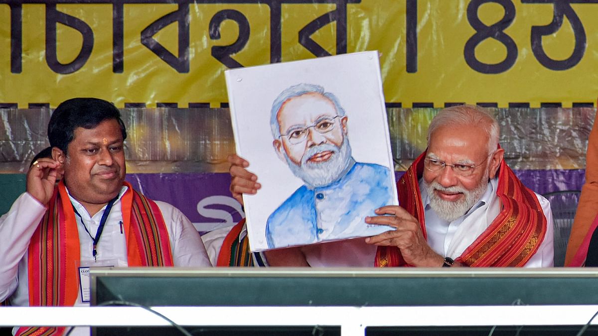 PM Modi showing his portrait which was presented to him at the rally.