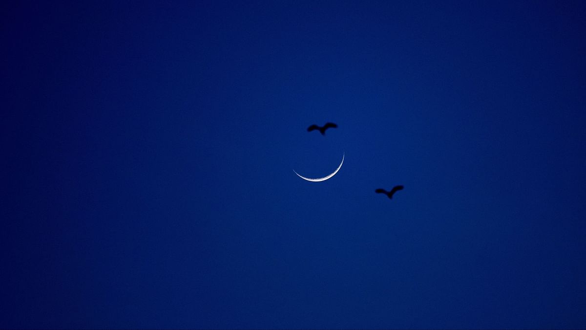 Birds fly next to a crescent moon that marks the end of the holy fasting month of Ramadan in Skopje, North Macedonia.