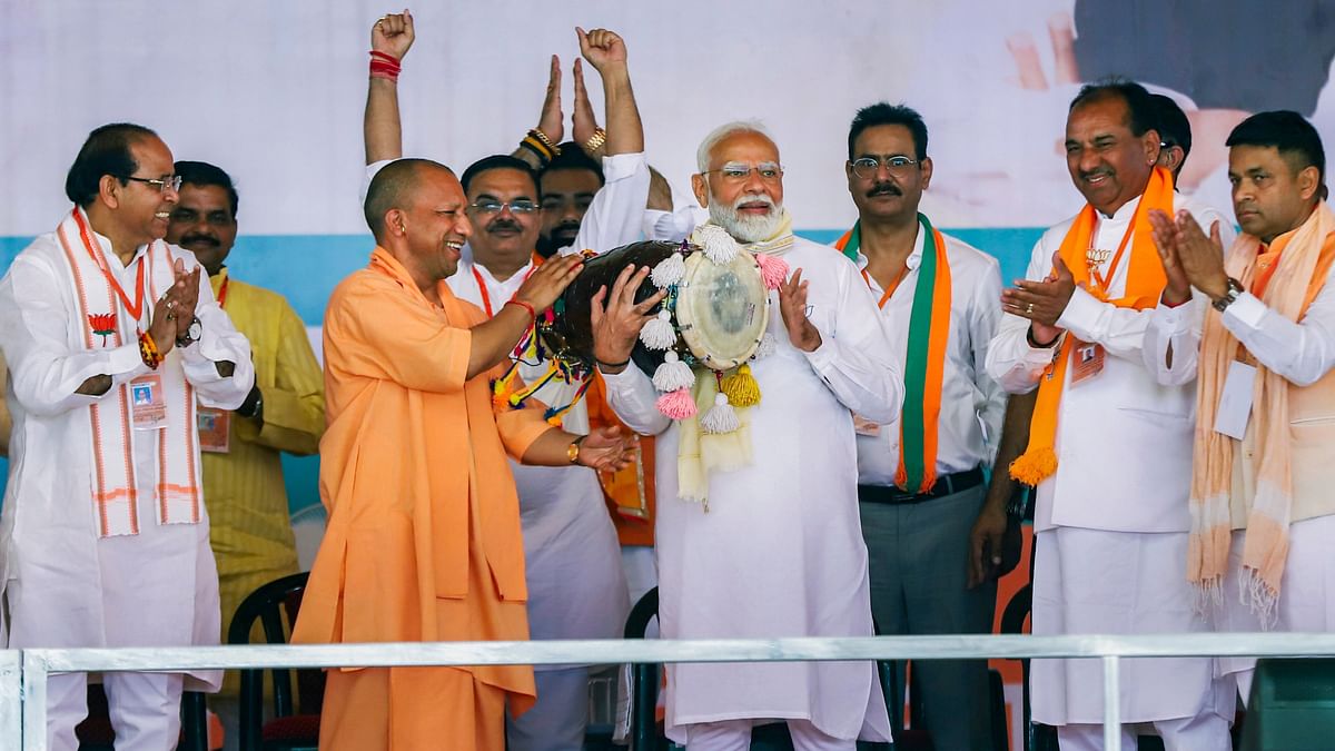 Prime Minister Narendra Modi plays the drum being given by Uttar Pradesh Chief Minister Yogi Adityanath during a public meeting for the Lok Sabha elections, at Gajraula in Amroha.