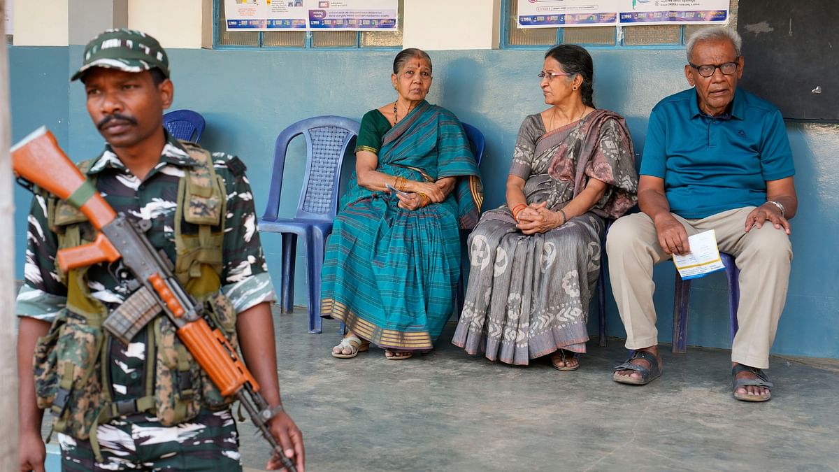 A security person guards as elderly people wait to cast their votes for the 2nd phase of Lok Sabha polls at a polling station at Rajarajeshwari Nagar, in Bengaluru.