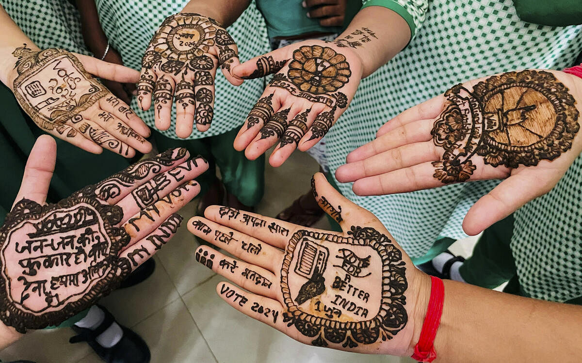 School students show their hands decorated with Henna (Mehendi) to create awareness on election voting ahead of the upcoming Lok Sabha polls, in Deoghar district, Saturday, April 6, 2024.