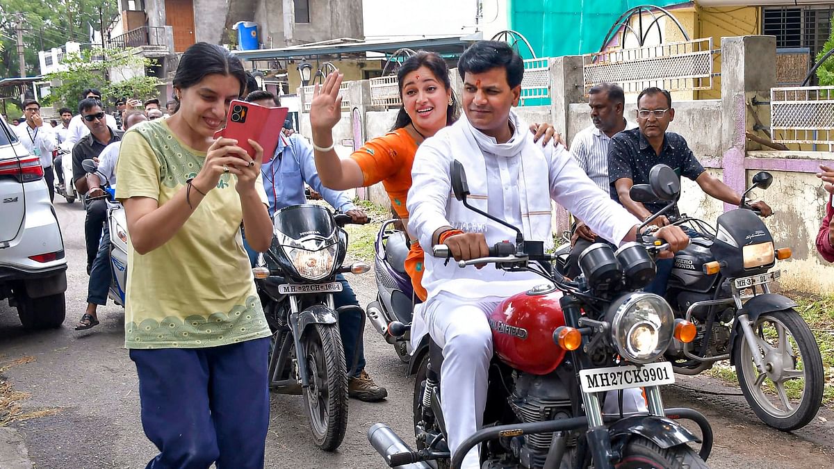  BJP candidate Navneet Rana with her husband MLA Ravi Rana arrives on motorbike to cast her vote 